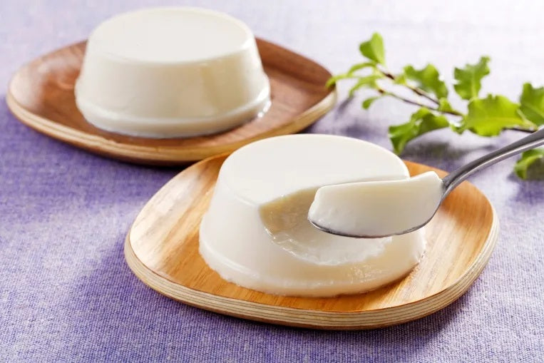 Hokkaido no-bake cheesecake with smooth texture on wooden plates, highlighting luxurious ingredients, rich cheese flavor, dairy and soybean allergens.