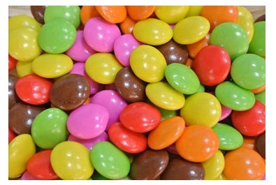 Colorful sugar-coated chocolates in vibrant pink, green, yellow, and orange hues, part of the Wanage Chocolate blister pack.
