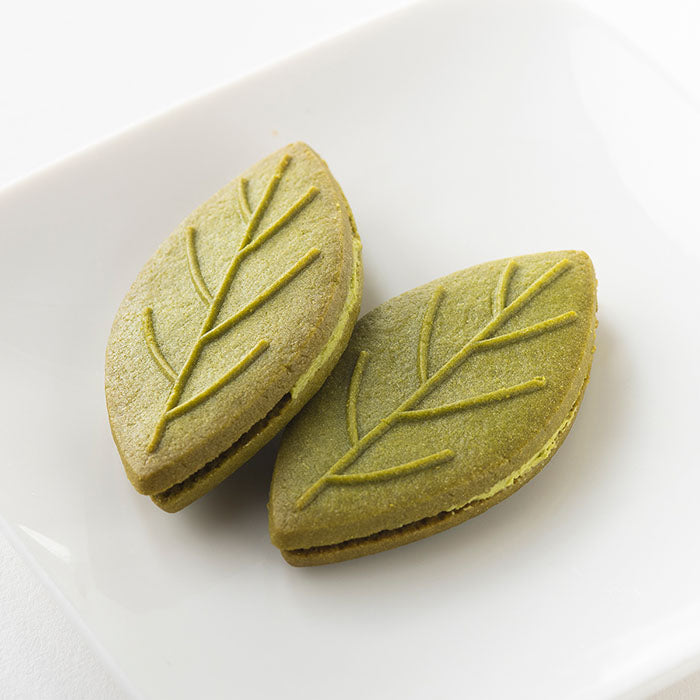 Shizuoka Green Tea Sandwich Cookies shaped like tea leaves, highlighting fresh tea flavor. Contains wheat, dairy, egg, soy.