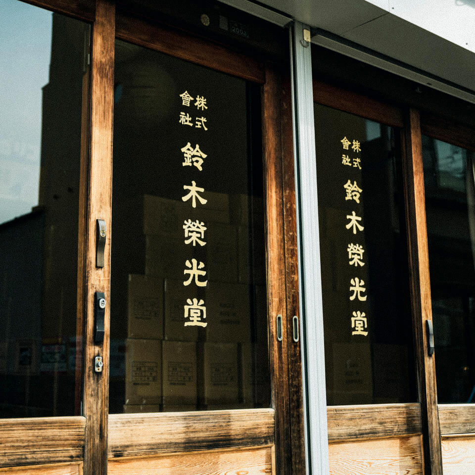 Wooden doors with Japanese text in gold lettering, reflecting a street scene.