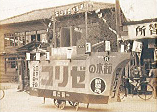 Vintage street scene with a promotional wagon, displaying Japanese text and advertisements from the early 20th century.