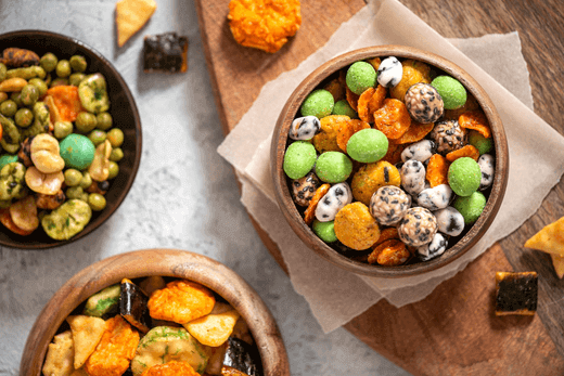 Assorted Japanese snacks in bowls featuring rice crackers, nuts, and seaweed, showcasing vibrant colors and textures.