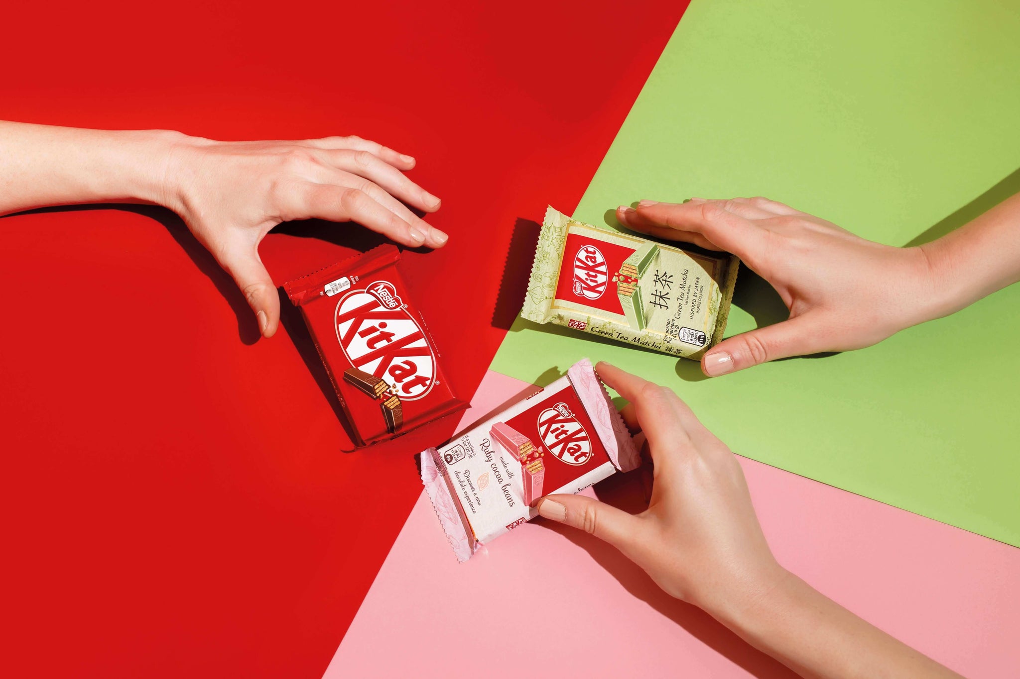 Hands exchanging Japanese KitKats with unique flavors on colorful background, showcasing Japan's innovative dessert culture.